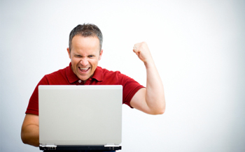 man with laptop cheering